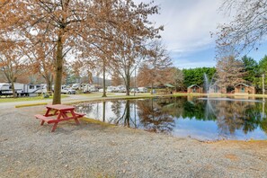A campsite with a picnic table, a pond, and RVs in the background. - Escape to Blue Ridge Mtns! Studio w/ Resort Perks (Waynesville)