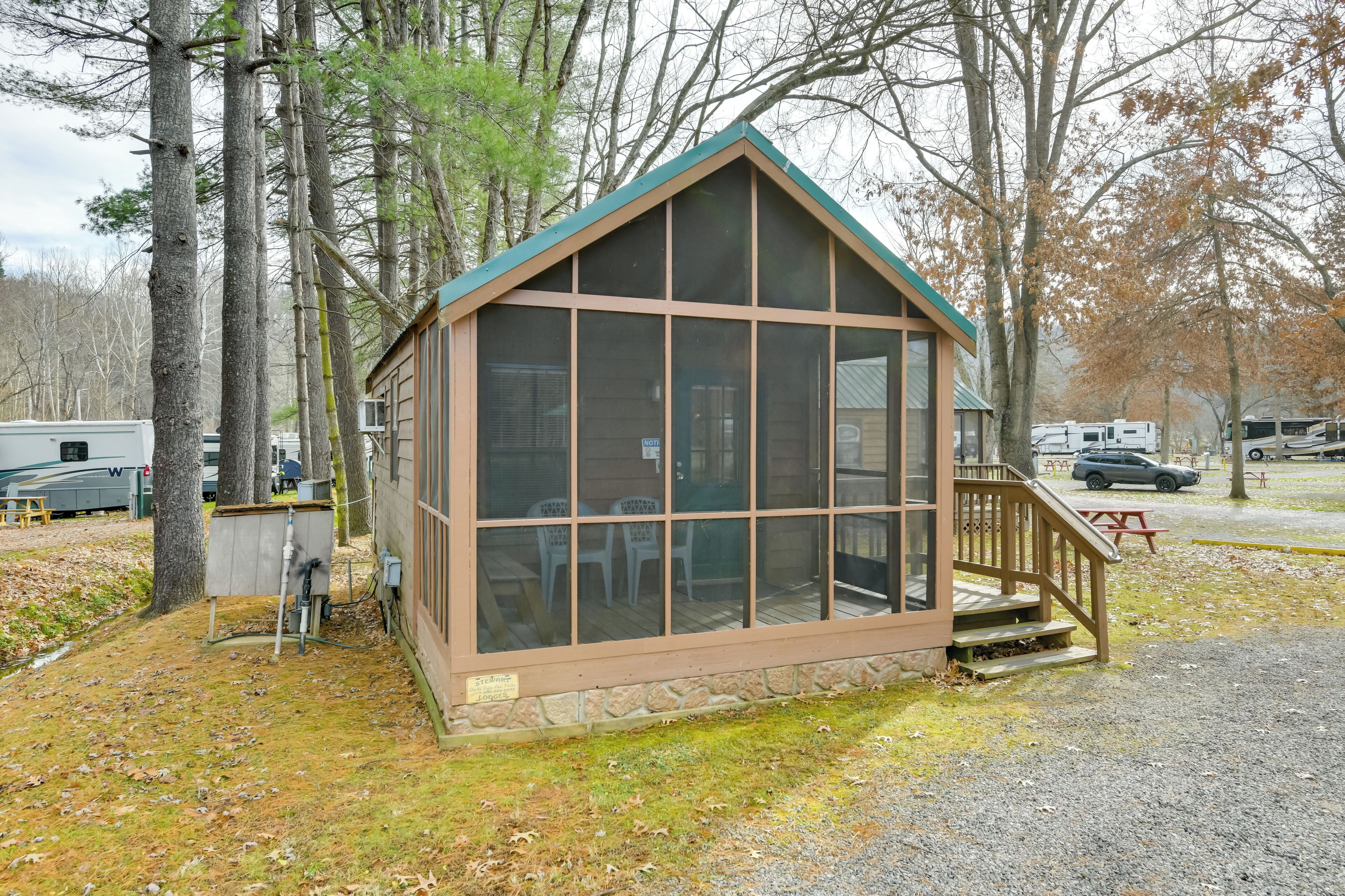 A small wooden cabin with a porch, surrounded by trees.