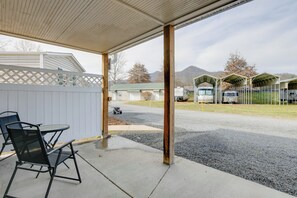 A covered outdoor area with a table and chairs, a view of a parking lot with RVs, and a mountain in the background. - Accessible Waynesville Studio Near Blue Ridge Pkwy (Waynesville)