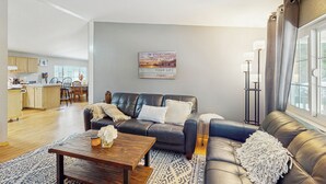 A living room with a sofa, coffee table, and a painting on the wall. - 4 BR Home w/ Backyard & Steps From the Lake (Shelton)