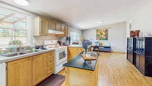 A modern kitchen with wooden cabinets, a black countertop, and a central island. - 4 BR Home w/ Backyard & Steps From the Lake (Shelton)