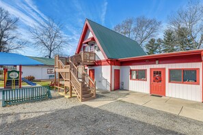 A building with a red and white exterior, a green roof, and a wooden staircase leading to a balcony. - Cataloochee Adventure Hub w/ Family-friendly Perks (Waynesville)