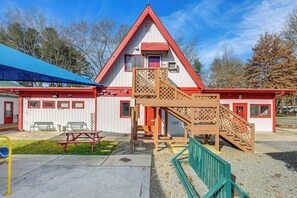 A building with a red and white exterior, a staircase, and a picnic table. - Cataloochee Adventure Hub w/ Family-friendly Perks (Waynesville)