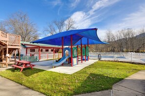A playground with a slide, a picnic table, and a covered play area. - Cataloochee Adventure Hub w/ Family-friendly Perks (Waynesville)
