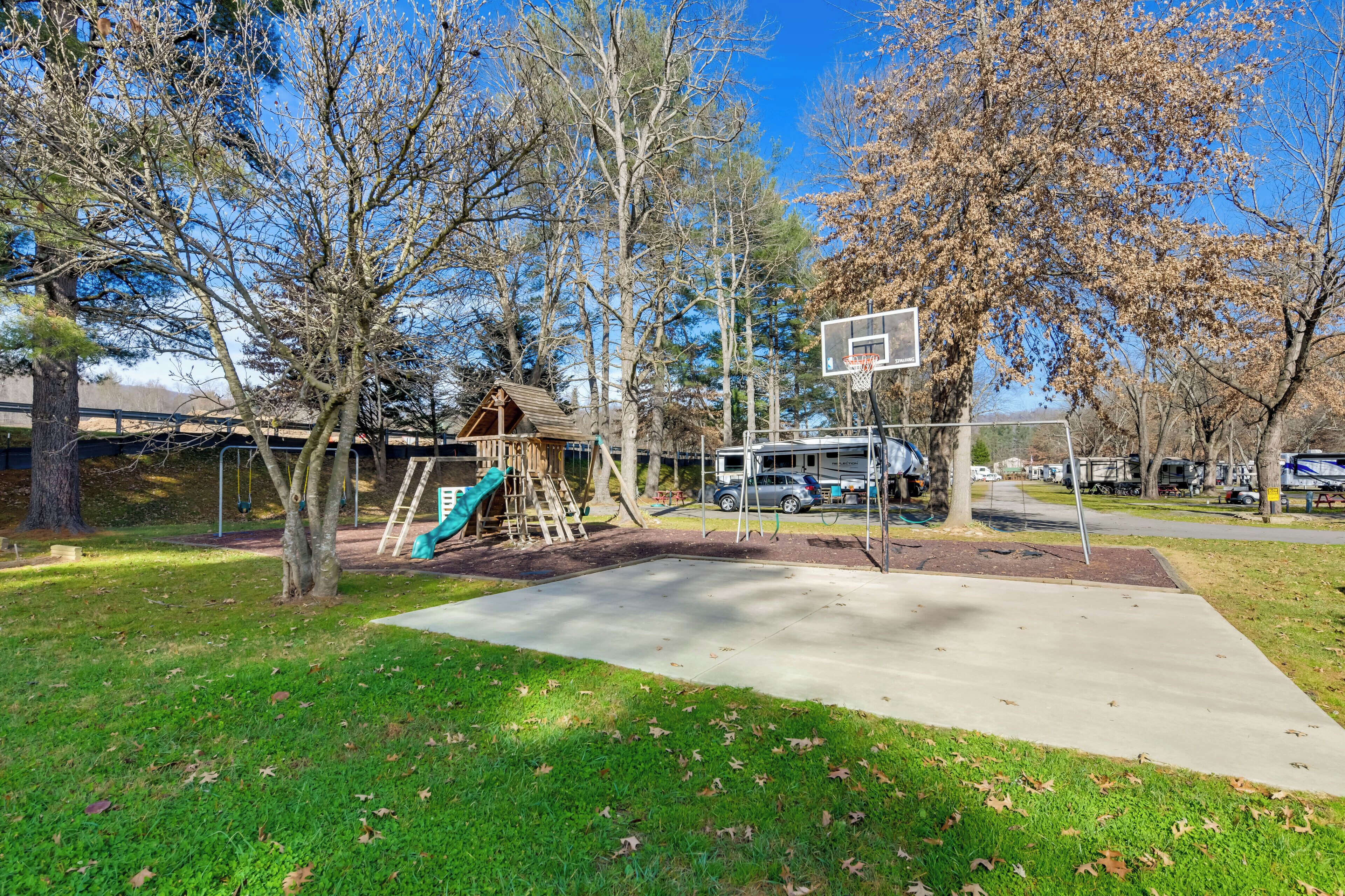 Un parque infantil con canasta de baloncesto, columpios y tobogán.