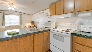 A kitchen with wooden cabinets, a white stove, a microwave, and a sink. - Mtn-view Adventure Hub! Waynesville Home w/ Perks (Waynesville)