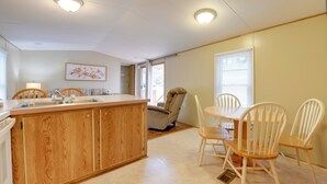 A kitchen with wooden cabinets, a sink, and a dining area with white chairs. - 13 Mi to Slopes! Group-friendly Blue Ridge Retreat (Waynesville)