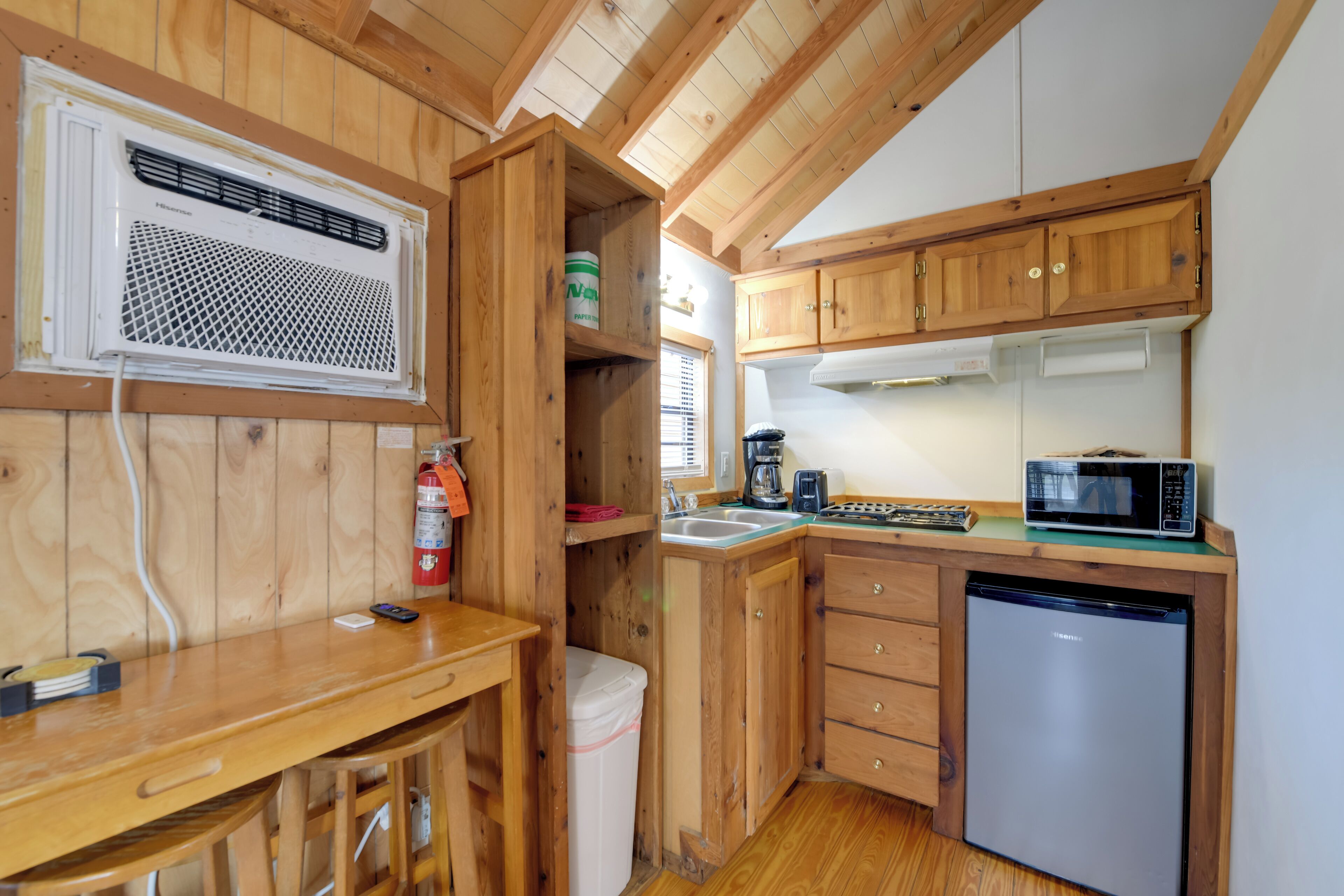 A compact kitchen with wooden cabinets, a microwave, a coffee maker, and a dishwasher.