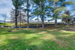 A park with trees, a grassy area, and a bridge in the background. - Blue Ridge Getaway! Studio w/ Resort Amenities (Waynesville)