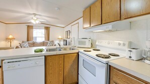 A modern kitchen with wooden cabinets, a white stove, a microwave, and a dishwasher. - Mtn-view Deck! Resort Cabin 12 Mi to Waynesville (Waynesville)