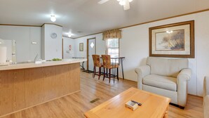 A spacious living area with a wooden coffee table, a beige armchair, and a dining table with chairs. A ceiling fan and recessed lighting are visible. - Mtn-view Deck! Resort Cabin 12 Mi to Waynesville (Waynesville)