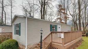 A single-story mobile home with a front porch, a small front yard, and a stone foundation. - Mtn-view Deck! Resort Cabin 12 Mi to Waynesville (Waynesville)