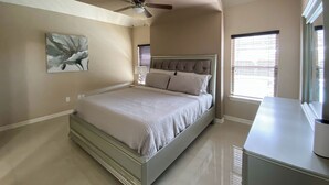 A bedroom with a bed, ceiling fan, artwork, window, and a dresser. - Pool, Patio & Yard: Chic South Texas Home (Olmito)