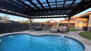 A backyard with a swimming pool, patio furniture, and a covered seating area. - Pool, Patio & Yard: Chic South Texas Home (Olmito)