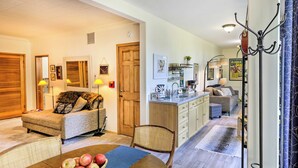 A cozy living room with a dining table, a sofa, and a kitchen area with a sink and cabinets. - Sunny Downtown Studio w/ Kitchenette & AC (Fairbanks)