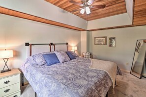 Un dormitorio con cama, mesitas de noche, ventilador de techo y espejo.