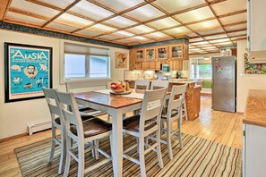 Una cocina moderna con armarios de madera, una mesa de comedor con sillas y un refrigerador.