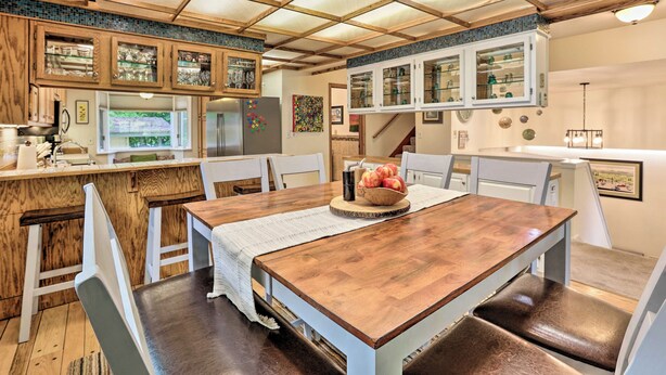 A dining area with a wooden table, white chairs, and a kitchen with wooden cabinets and a tiled backsplash. - Vibrant 3BR Near Downtown w/ Fireplaces (Fairbanks)