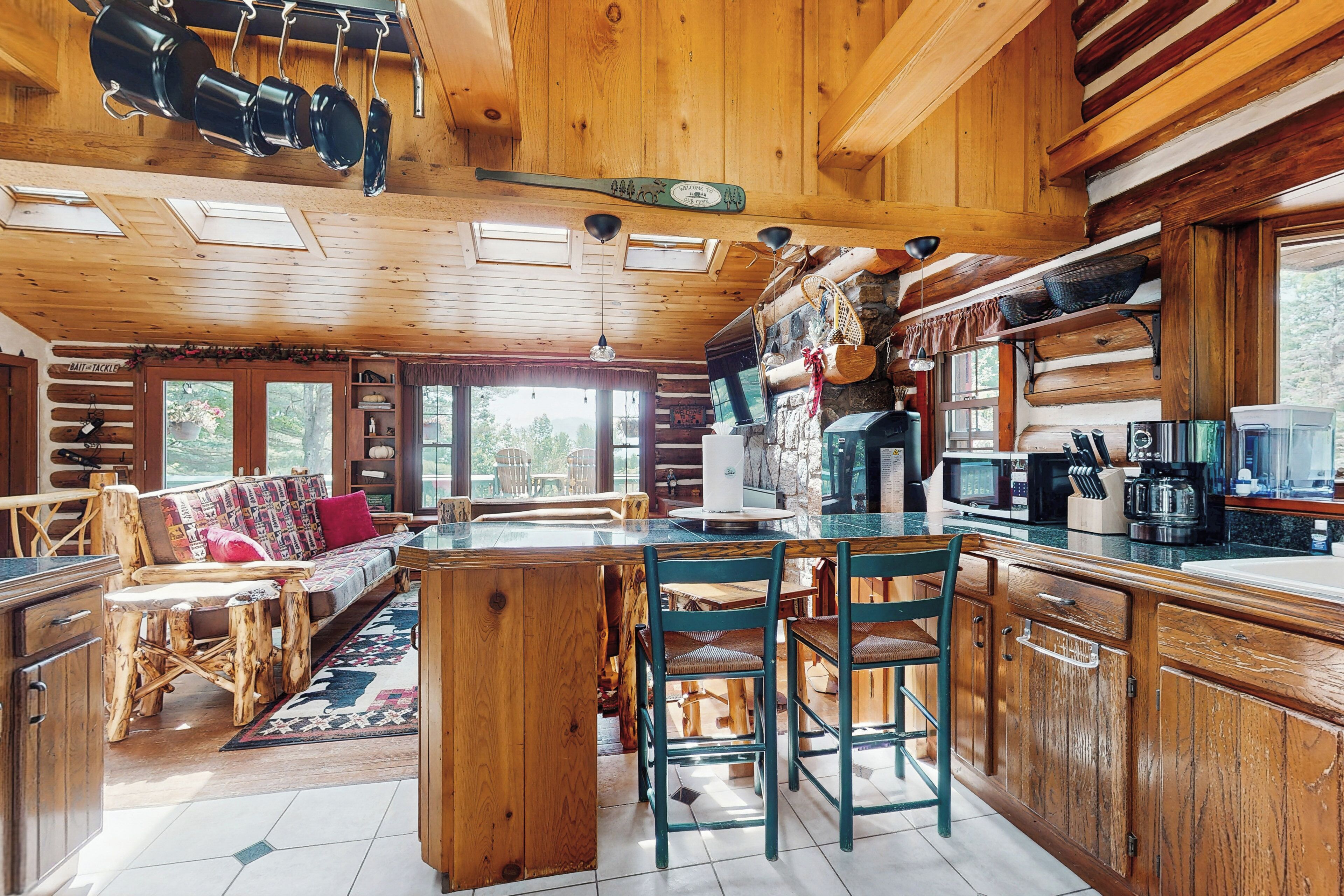 Ein rustikales Blockhaus-Interieur mit einer Essnische aus Holz, einer zentralen Kochinsel und einer Küche mit modernen Geräten.