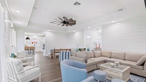 A modern living room with a sectional sofa, a blue armchair, and a glass coffee table. - Bring Your Boat! Lake Charles Home w/ Dock & Lift (Lake Charles)