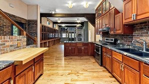 A kitchen with wooden cabinets, a wooden countertop, and a brick wall. - Deck, Views, Games: 10br Home in Shenandoah Valley (McDowell)