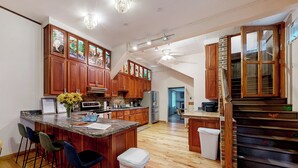 A spacious kitchen with wooden cabinets, a central island with bar stools, a staircase, and a view to the dining area. - Deck, Views, Games: 10br Home in Shenandoah Valley (McDowell)