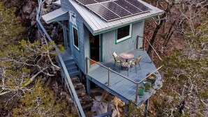 A small cabin with a solar panel roof, a deck with outdoor seating, and a staircase leading up to it. - Deck, Views, Games: 10br Home in Shenandoah Valley (McDowell)
