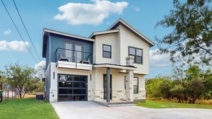 A two-story house with a garage, a balcony, and a stone pillar. - Modern Living in Texas! Home 2 Blocks to Lake LBJ (Marble Falls)