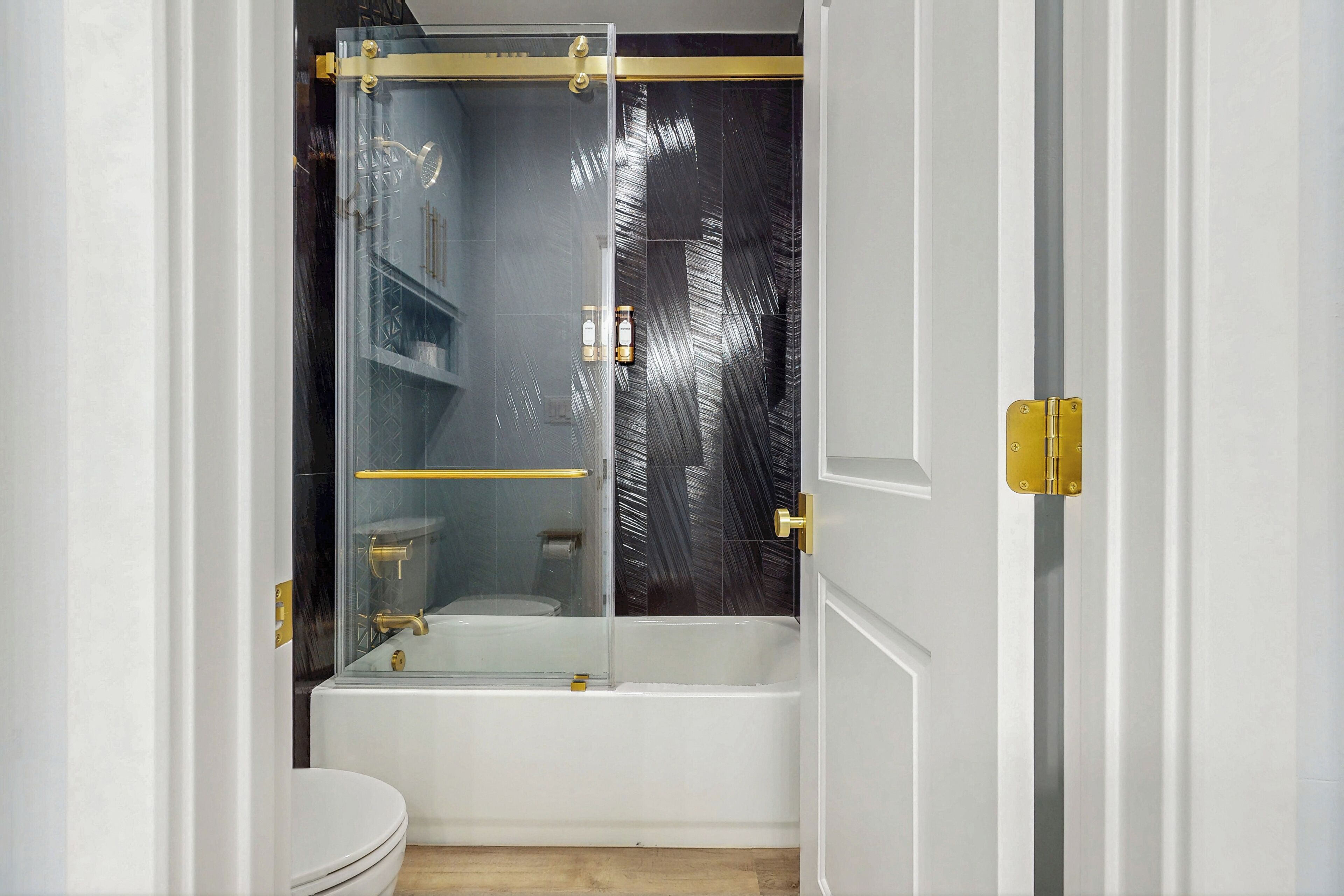 A bathroom with a glass-enclosed shower, a white bathtub, and a toilet.