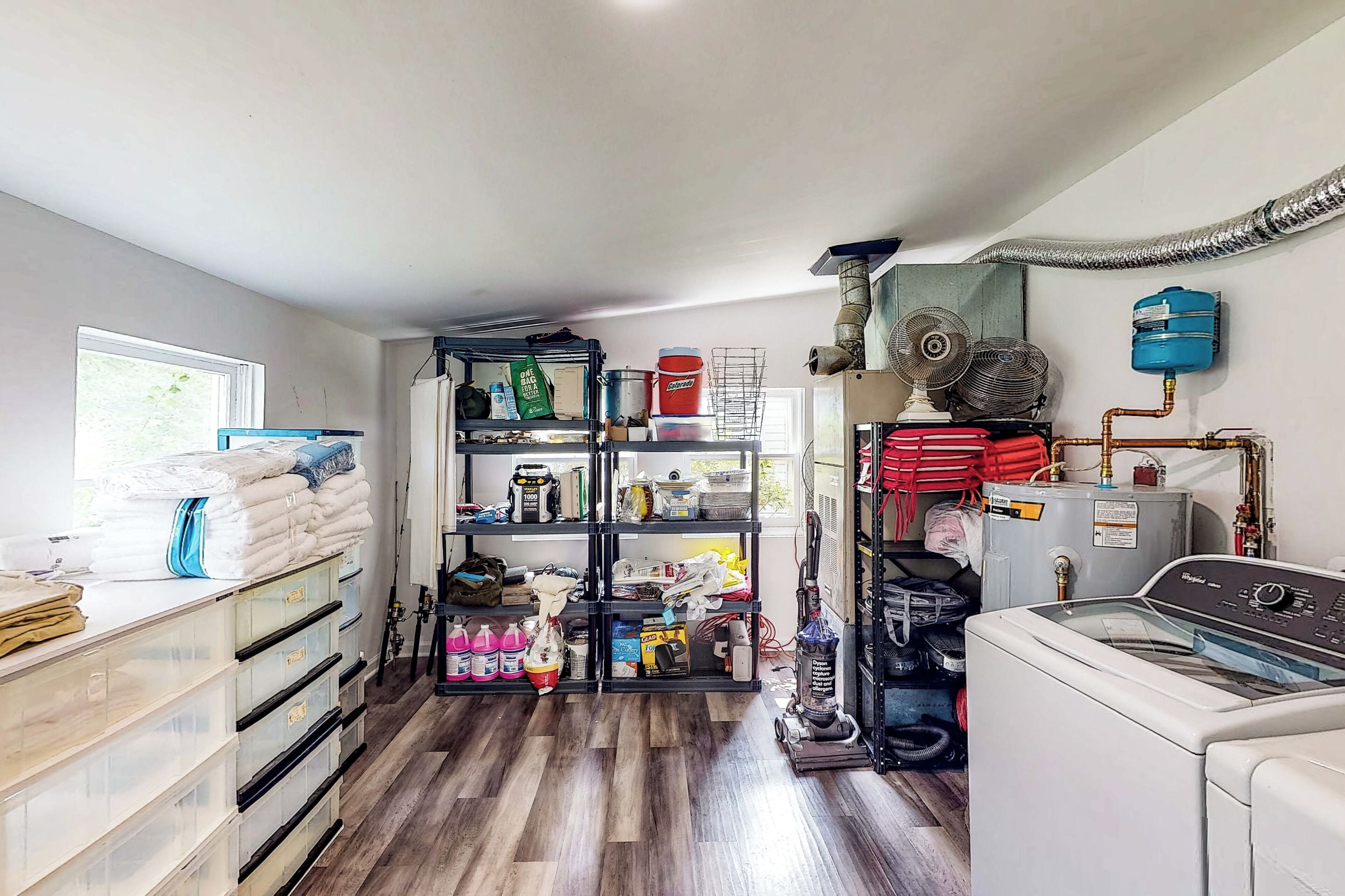 A laundry room with a washing machine, shelves with cleaning supplies, and a water heater.