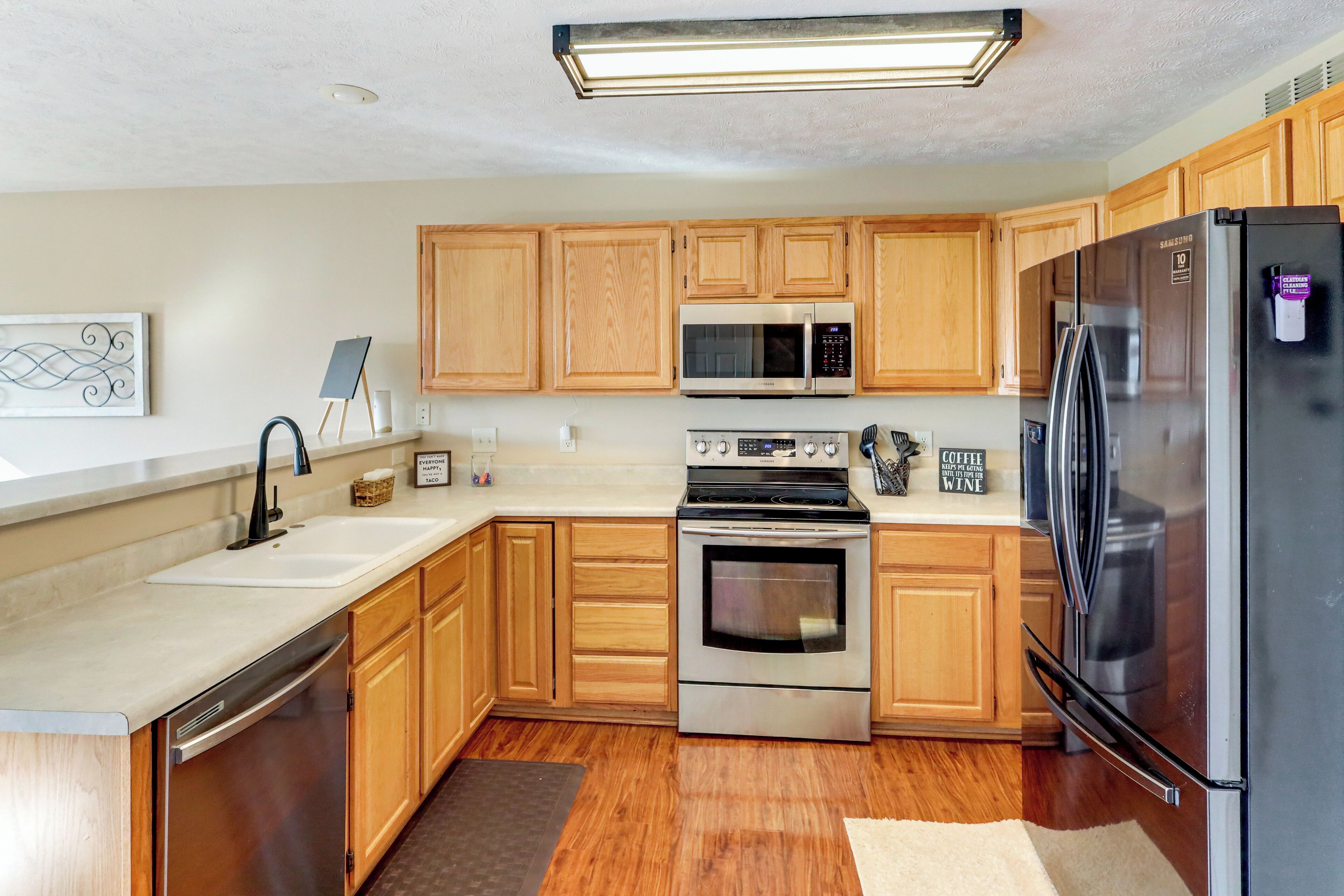 A modern kitchen with wooden cabinets, stainless steel appliances, and a dishwasher.