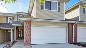 A two-story residential building with a garage, brick columns, and a front door with a tree decal. - 4 Mi to Memorial Stadium: Family Escape in Lincoln (Lincoln)