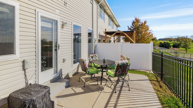 A patio with a table and chairs, a covered area, and a view of a green landscape. - 4 Mi to Memorial Stadium: Family Escape in Lincoln (Lincoln)