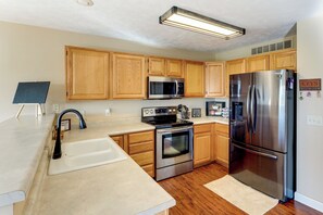 A modern kitchen with wooden cabinets, stainless steel appliances, a black faucet, and a chalkboard.