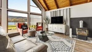 Un salon spacieux doté d’une grande fenêtre, d’une cheminée, d’un téléviseur et d’un coin salon confortable.