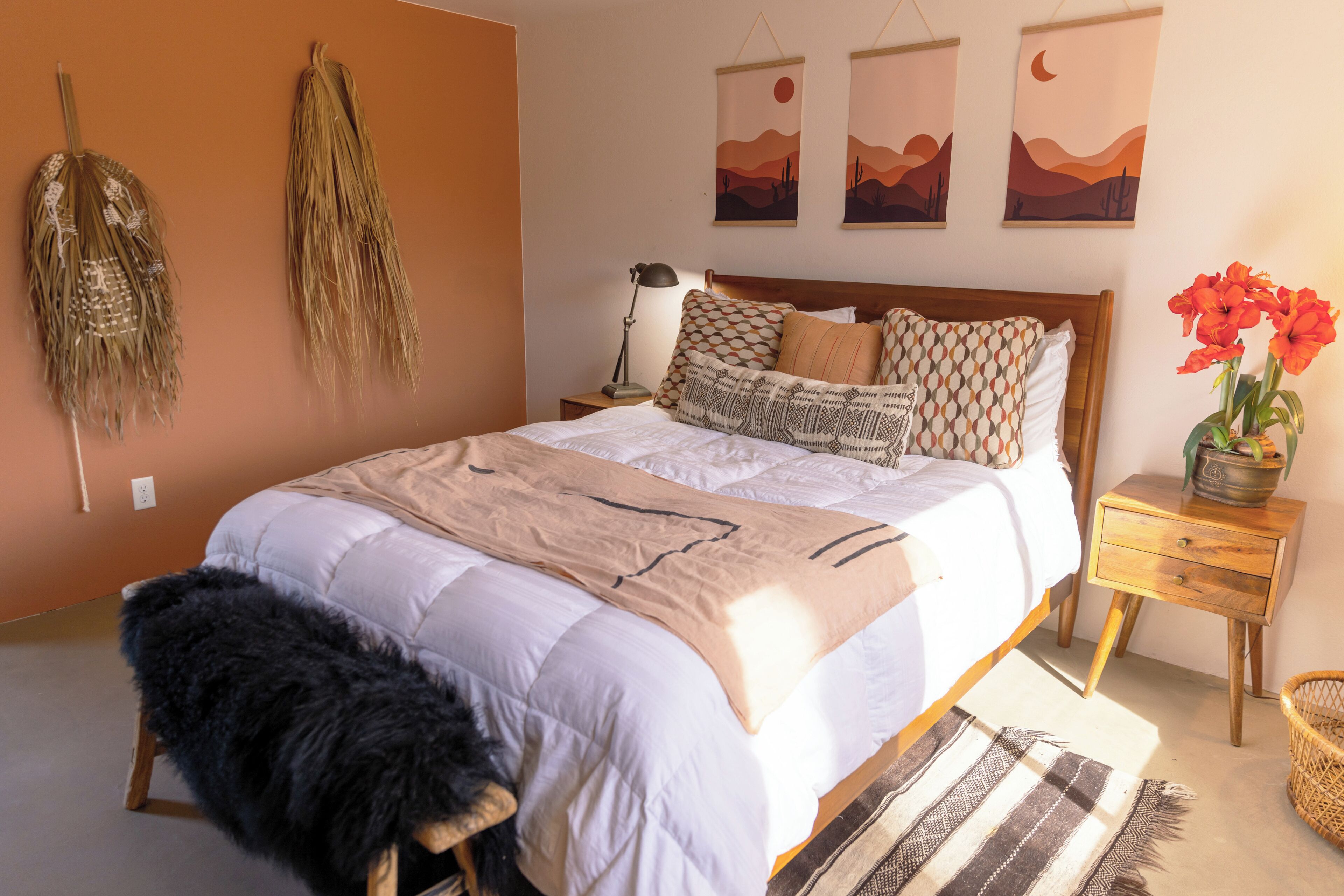 A bedroom with a bed, a nightstand, a lamp, and wall art.