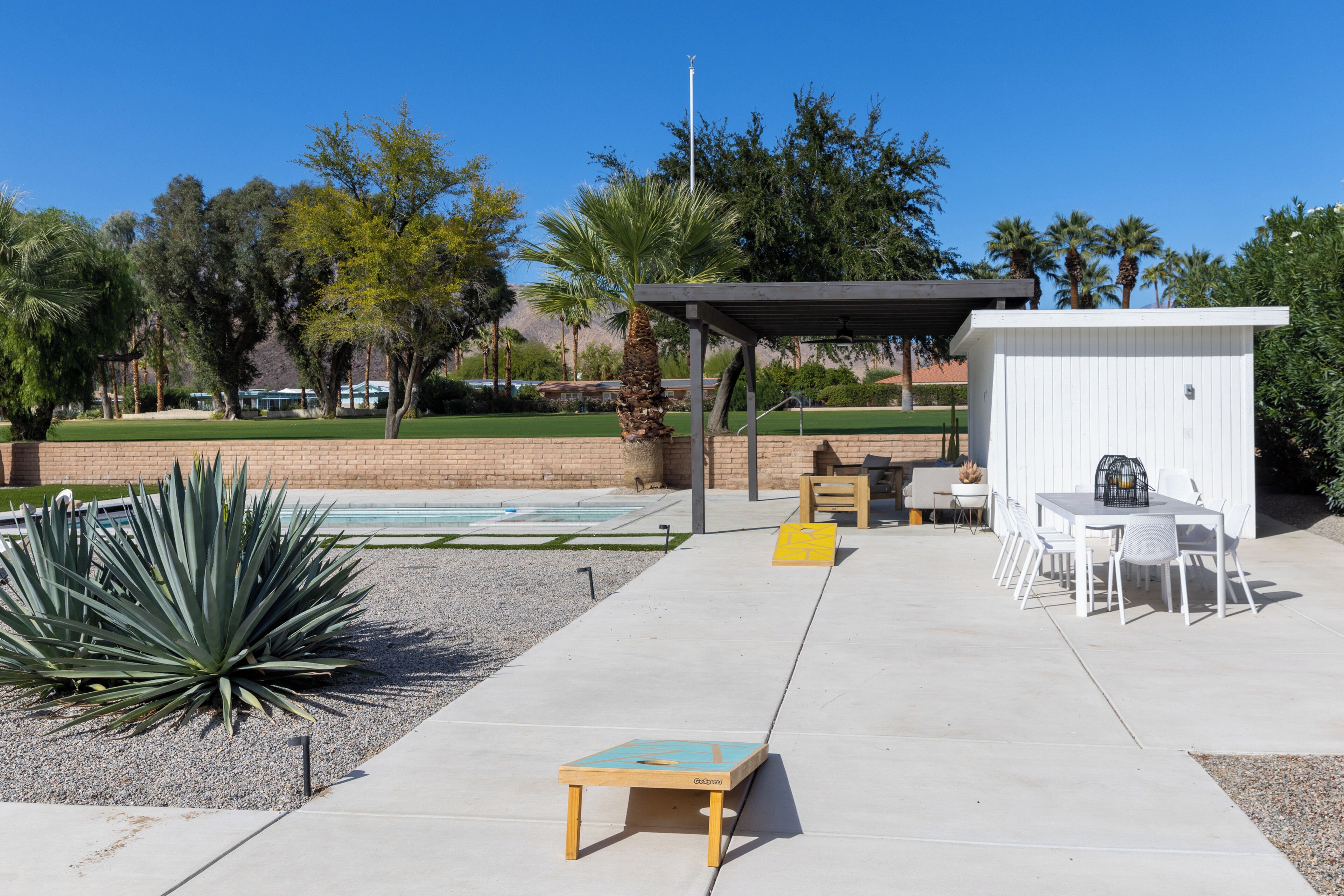 An outdoor patio area with a pool, seating, and a small building.