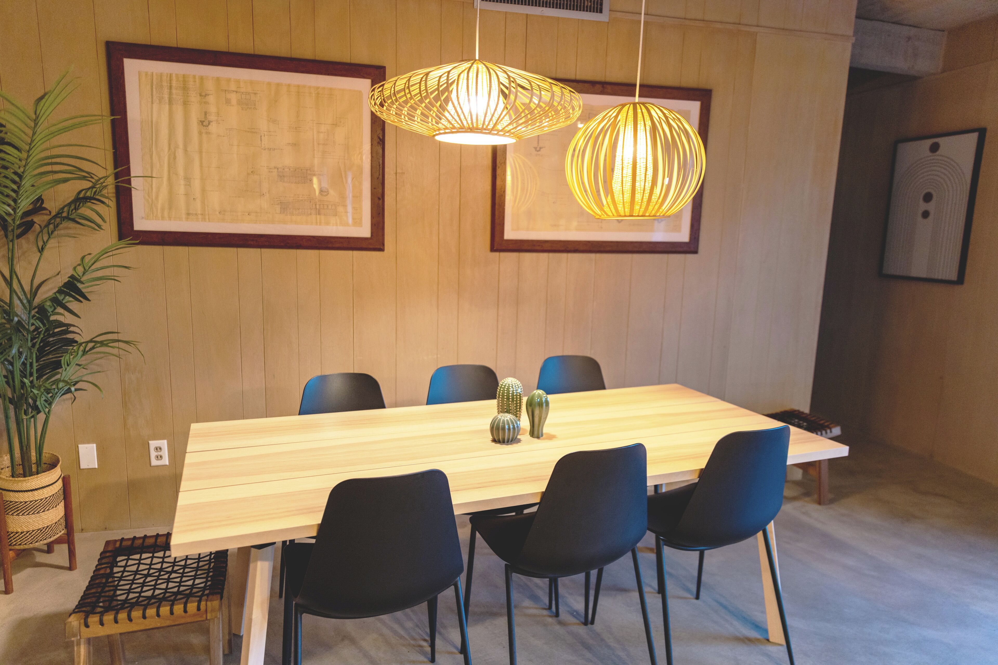 A dining area with a wooden table, black chairs, and hanging pendant lights.