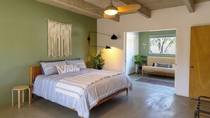 A bedroom with a bed, a ceiling fan, a wall-mounted light, a macrame wall hanging, and a view of a green door leading outside. - 3BR Designer Hideaway w/ Private Pool, spa (Borrego Springs)