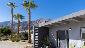 A modern building with a dark facade, a wooden deck, and a mountain backdrop. - 3BR Designer Hideaway w/ Private Pool, spa (Borrego Springs)