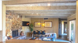 A spacious living area with a stone fireplace, a dining table with chairs, and a sofa. - 3BR Designer Hideaway w/ Private Pool, spa (Borrego Springs)