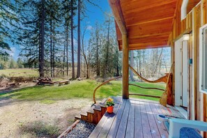 A wooden deck with a bench, a potted plant, and a broom leaning against the wall. - Romantic 15-acre Hideout Near Foster Creek! (Toledo)
