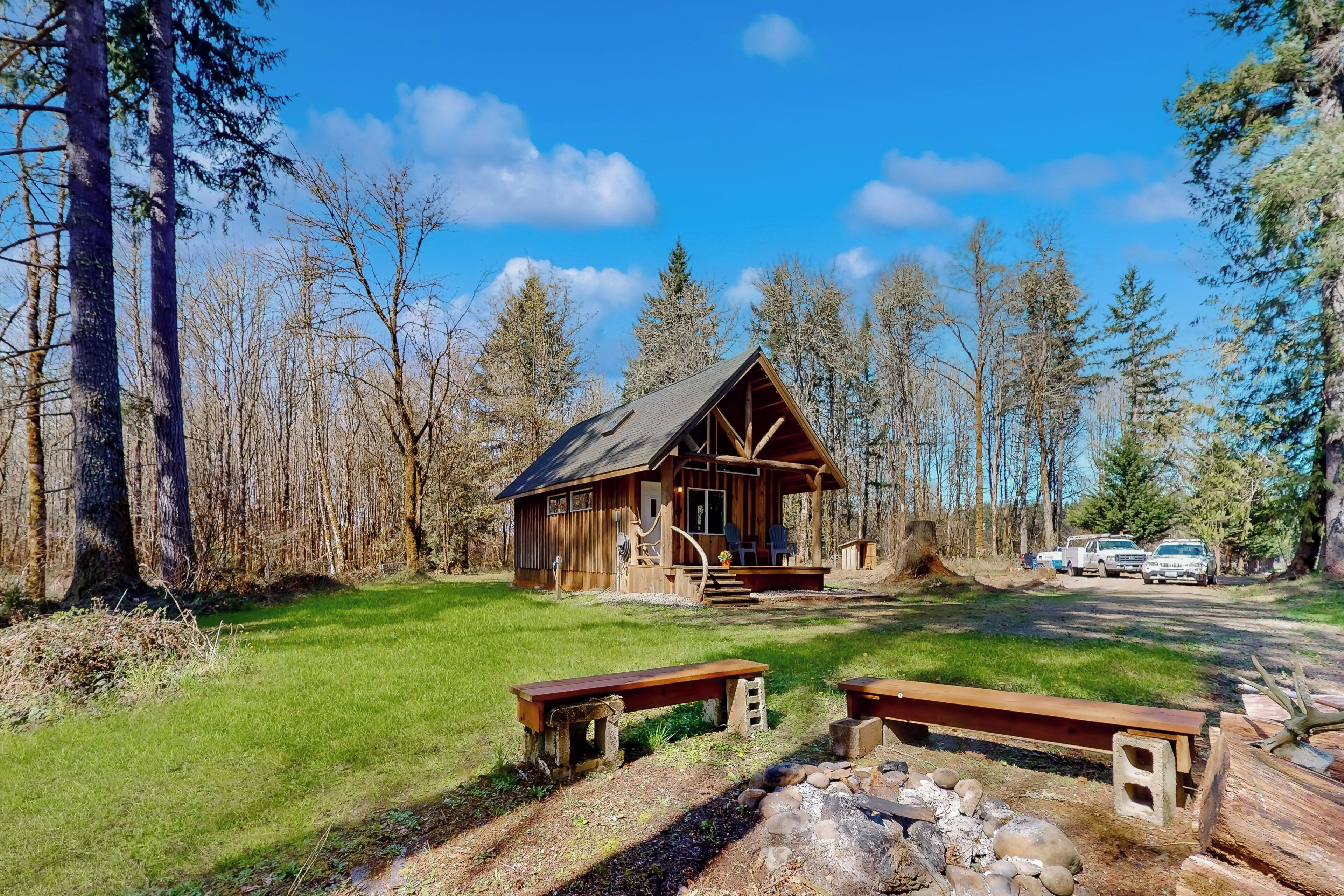 A rustic cabin with a wooden exterior, a porch, and a stone fire pit area.