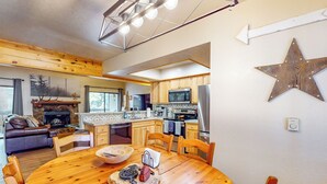 Una cocina moderna con armarios de madera, una isla grande y una zona de comedor con mesa y sillas de madera.