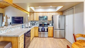 Una cocina compacta con armarios de madera, microondas, refrigerador y estufa.