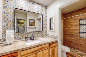 A bathroom with a tiled backsplash, a large mirror, a sink, wooden cabinets, and a wooden shower enclosure. - 3BR Condo w/ Fire Pit & Full Kitchen (Pinetop)