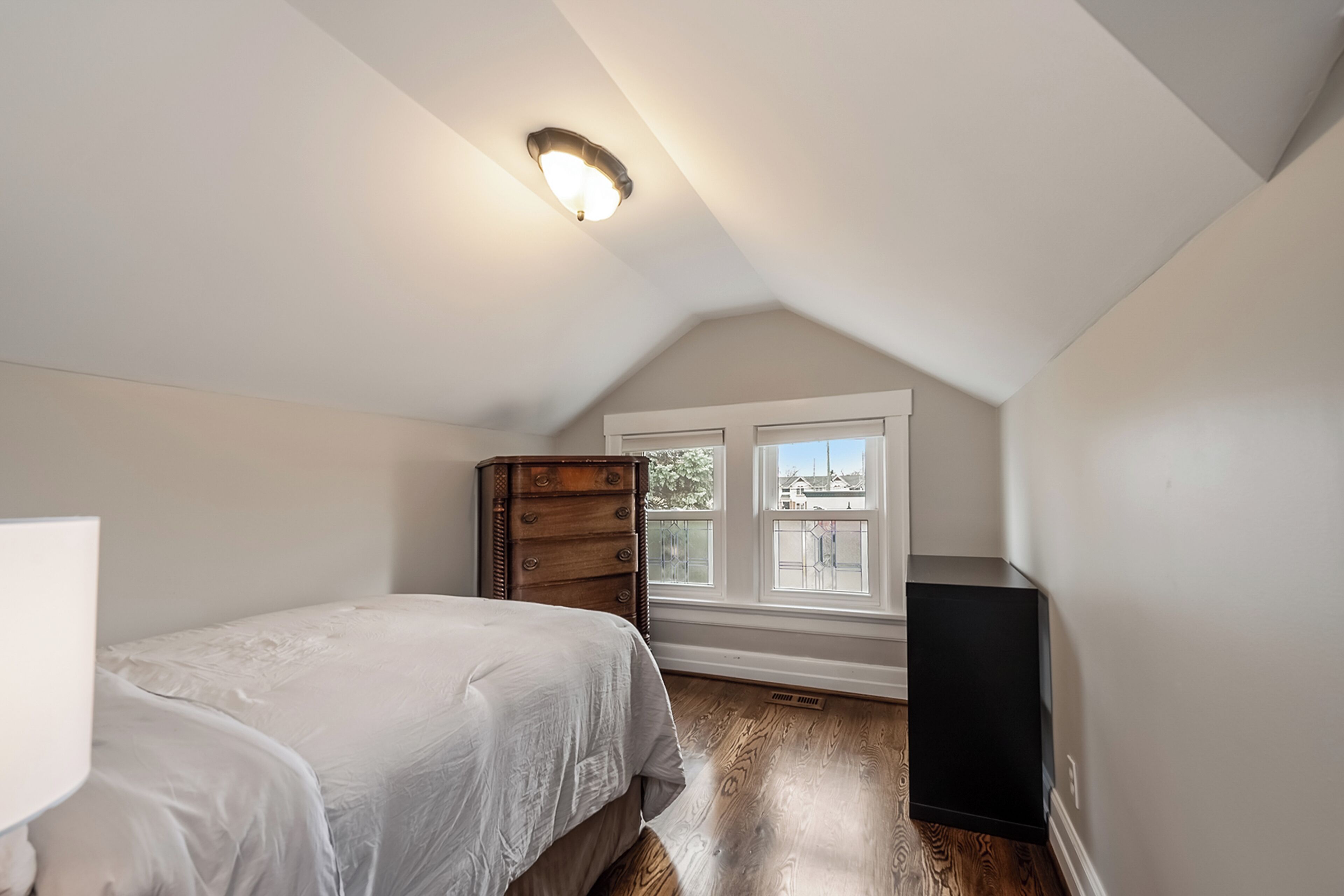Une chambre à coucher avec un lit, une commode et une fenêtre donnant sur un beau paysage.