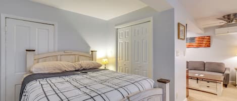 A bedroom with a bed, a nightstand, a dresser, a ceiling fan, and an American flag on the wall.