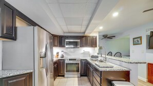 A modern kitchen with stainless steel appliances, dark wooden cabinets, and a granite countertop. - Pet-friendly Apt Near Ocoee River & Waterfalls (Etowah)