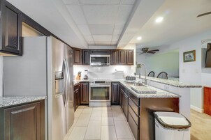Una cocina moderna con electrodomésticos de acero inoxidable, gabinetes de madera oscura y encimera de granito.